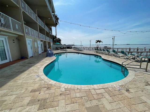 view of swimming pool with a patio area and a water view