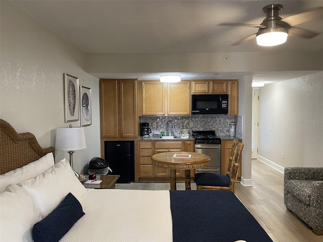 kitchen featuring ceiling fan, stainless steel range, sink, tasteful backsplash, and light hardwood / wood-style flooring