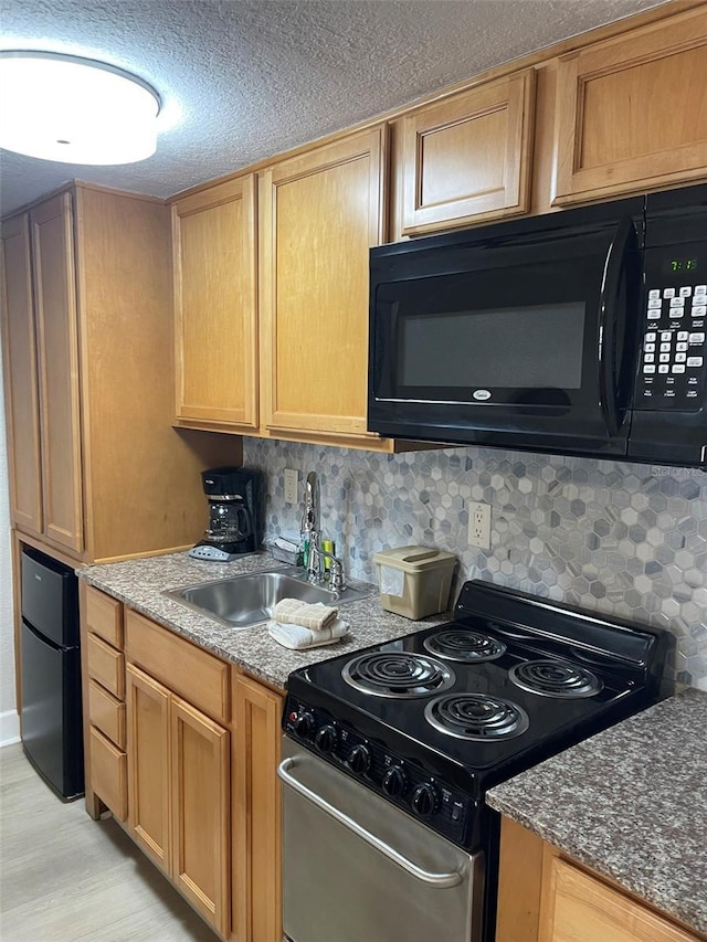 kitchen with electric range, sink, dark stone counters, and fridge