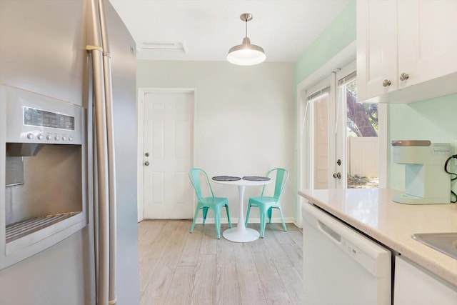6490 34th Ave N, Saint Petersburg, FL 33710 - kitchen with decorative light fixtures, white cabinetry, dishwasher, stainless steel refrigerator with ice dispenser, and light hardwood / wood-style flooring