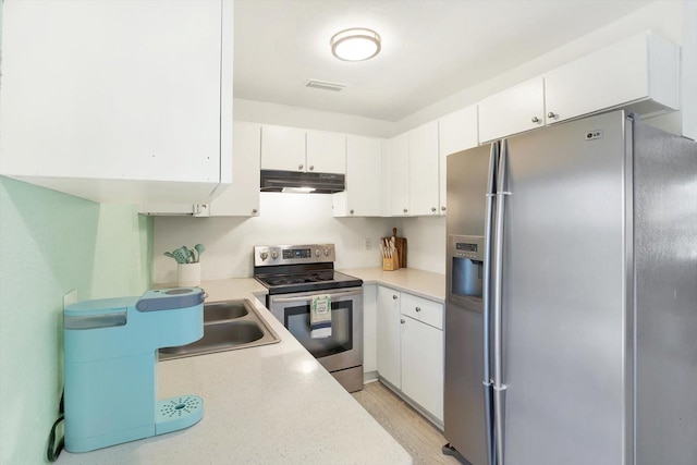 6490 34th Ave N, Saint Petersburg, FL 33710 - kitchen with white cabinetry, appliances with stainless steel finishes, sink, and light hardwood / wood-style flooring