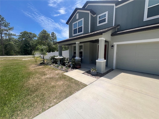 view of front of home with a garage, covered porch, and a front yard