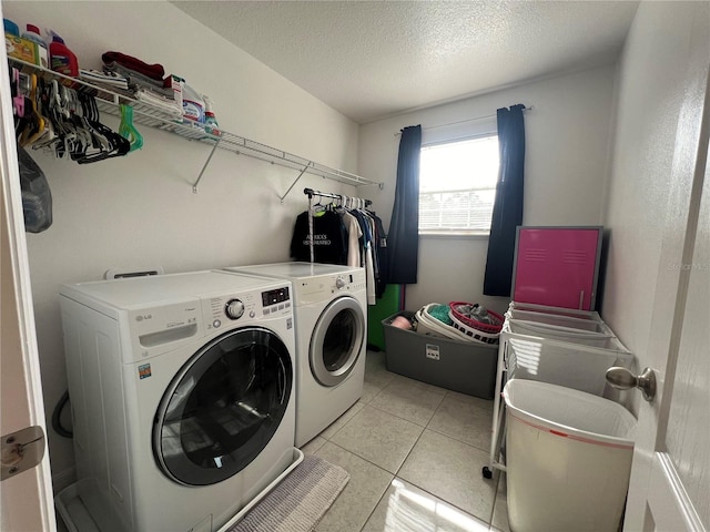 washroom with light tile patterned flooring, washer and dryer, and a textured ceiling