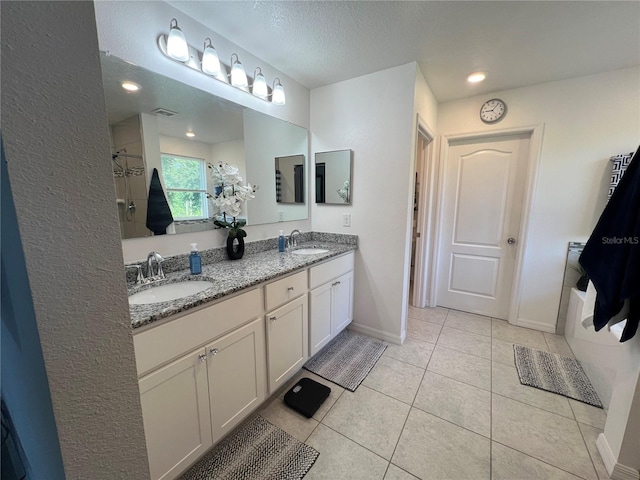 bathroom featuring tile patterned flooring, a textured ceiling, vanity, and a shower