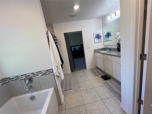 bathroom featuring tile patterned flooring, vanity, a textured ceiling, and a tub