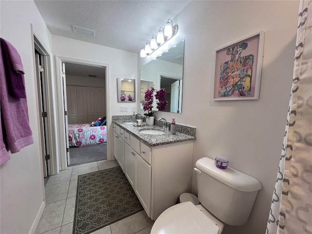 bathroom featuring tile patterned floors, vanity, a textured ceiling, and toilet