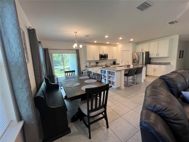 dining room with sink, light tile patterned floors, and an inviting chandelier