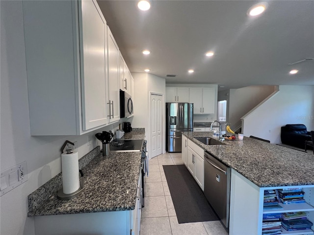 kitchen with sink, stainless steel appliances, white cabinets, a kitchen island with sink, and light tile patterned flooring