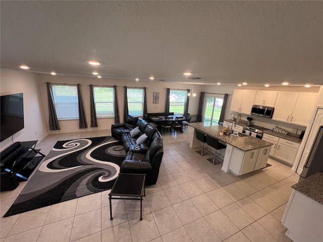 kitchen with dark stone counters, a center island with sink, a kitchen breakfast bar, white cabinets, and stainless steel appliances