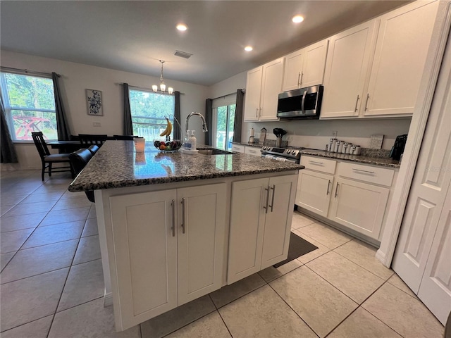 kitchen featuring a kitchen island with sink, sink, light tile patterned floors, and stainless steel appliances