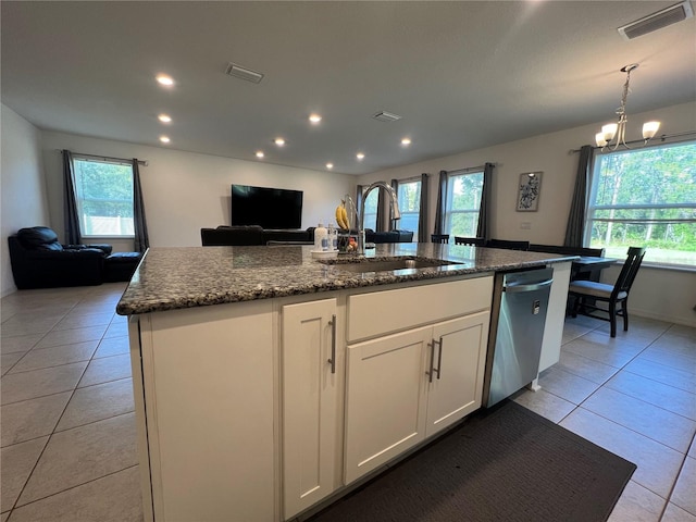 kitchen featuring sink, light tile patterned floors, stainless steel dishwasher, a center island with sink, and white cabinets