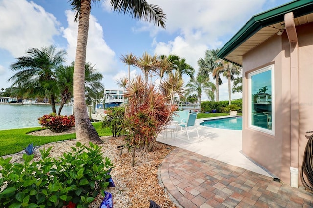 view of swimming pool featuring a patio and a water view