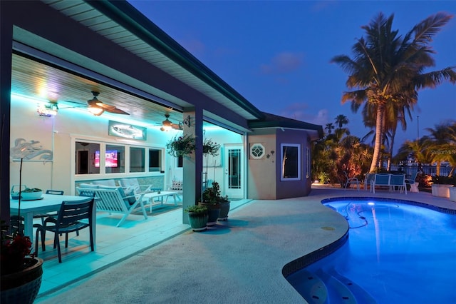 pool at dusk with ceiling fan, an outdoor hangout area, and a patio area