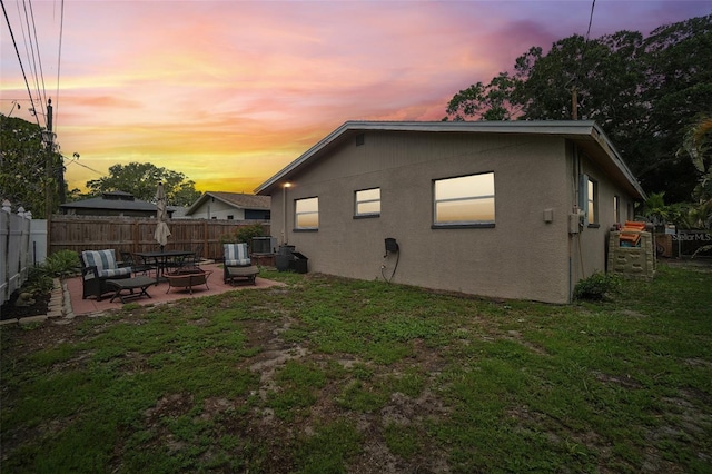 back house at dusk with a yard, a patio, and central air condition unit