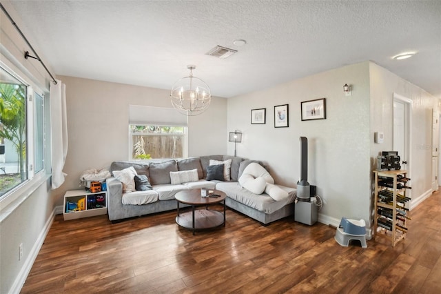 living room featuring an inviting chandelier, a healthy amount of sunlight, dark hardwood / wood-style flooring, and a textured ceiling