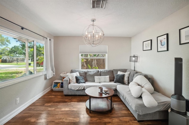 living room featuring dark hardwood / wood-style flooring, a notable chandelier, and a textured ceiling