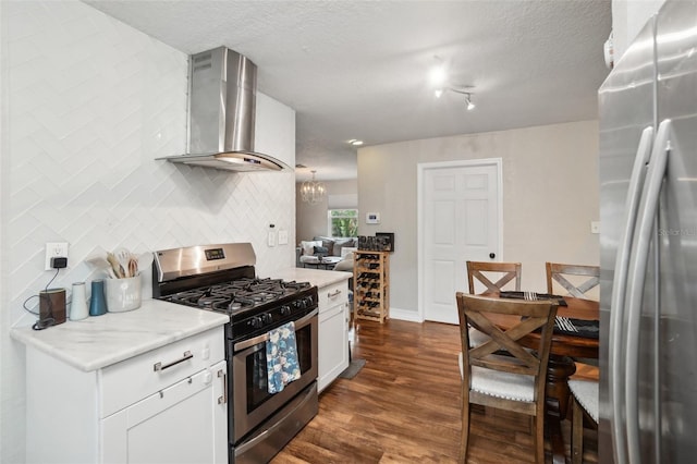 kitchen featuring appliances with stainless steel finishes, dark hardwood / wood-style floors, white cabinetry, backsplash, and wall chimney range hood