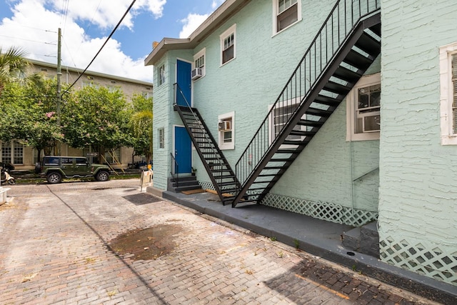 view of side of home with stucco siding, stairway, and entry steps