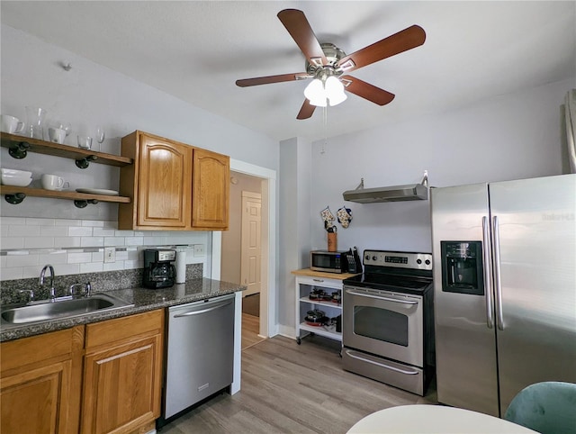 kitchen featuring appliances with stainless steel finishes, tasteful backsplash, sink, ceiling fan, and light wood-type flooring