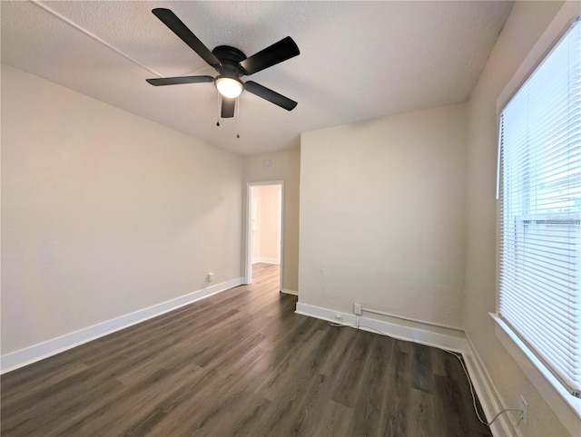 spare room with ceiling fan, baseboards, and dark wood finished floors