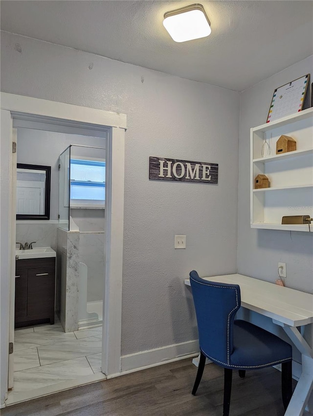 home office featuring sink, light hardwood / wood-style floors, and a textured ceiling