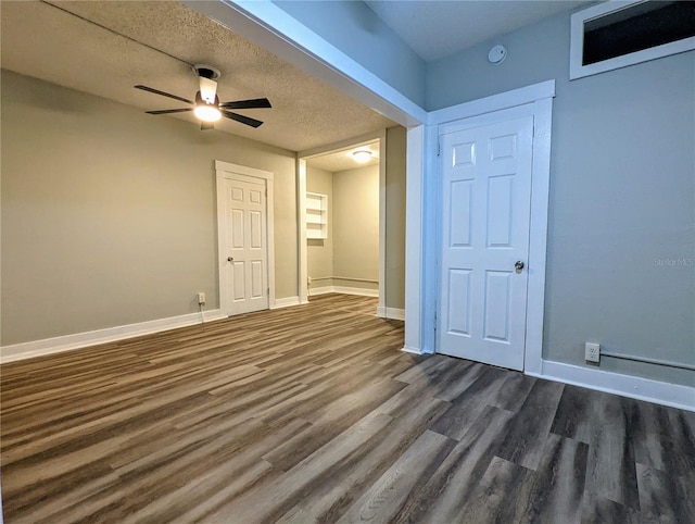 unfurnished room with a textured ceiling, dark wood-type flooring, and ceiling fan