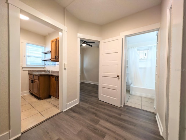 corridor with wood finished floors, baseboards, and a sink