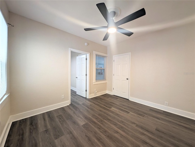 unfurnished room featuring baseboards, dark wood-type flooring, and a ceiling fan