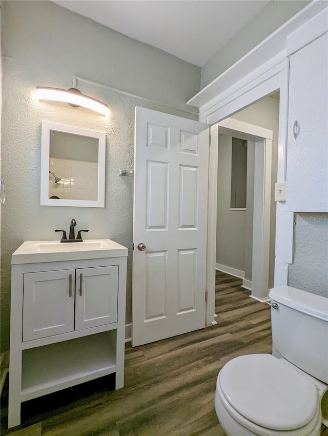 bathroom featuring toilet, wood finished floors, vanity, and a textured wall