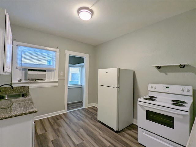 kitchen featuring baseboards, cooling unit, wood finished floors, white appliances, and a sink