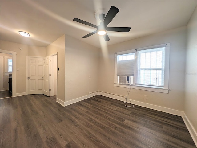 empty room featuring cooling unit, baseboards, dark wood finished floors, and a ceiling fan