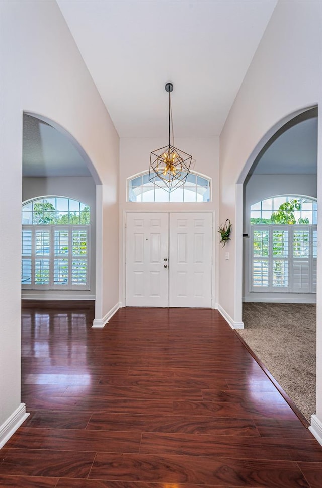 entryway with vaulted ceiling, dark wood-type flooring, and a notable chandelier