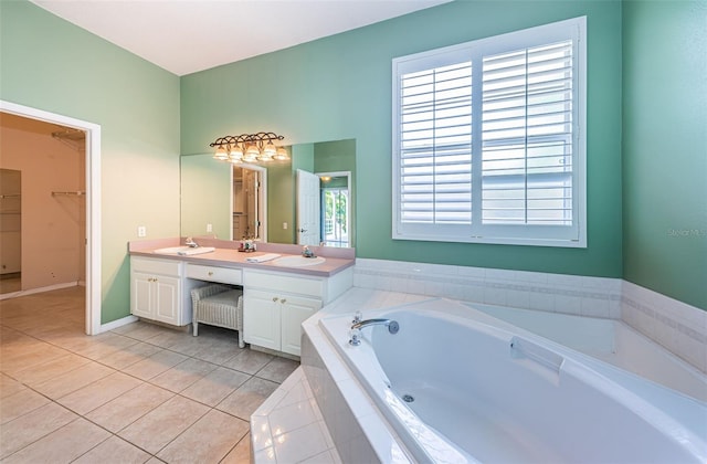 bathroom with double vanity, tile patterned floors, a garden tub, a walk in closet, and a sink