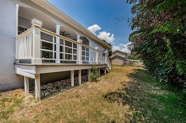 rear view of property with a yard, ceiling fan, and stucco siding