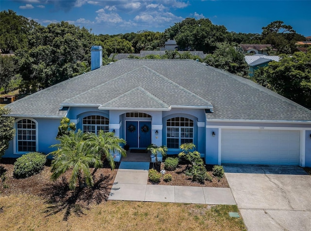 ranch-style home featuring a garage, driveway, roof with shingles, and a chimney