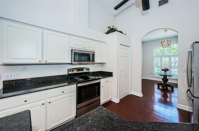 kitchen featuring dark stone counters, stainless steel appliances, visible vents, and white cabinetry