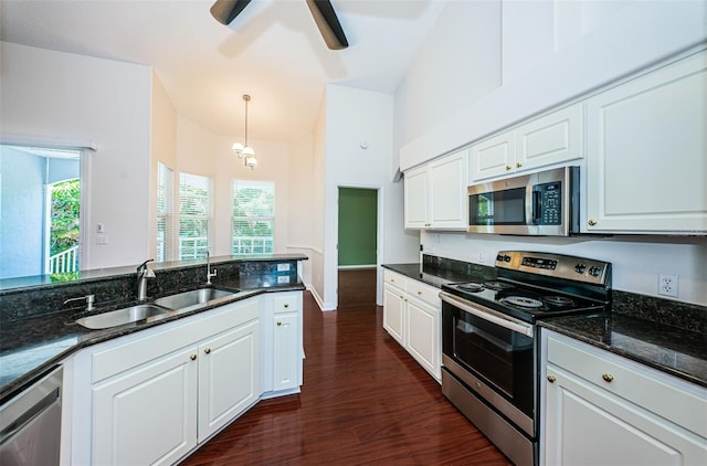 kitchen with stainless steel appliances, dark wood-style flooring, a sink, and white cabinetry