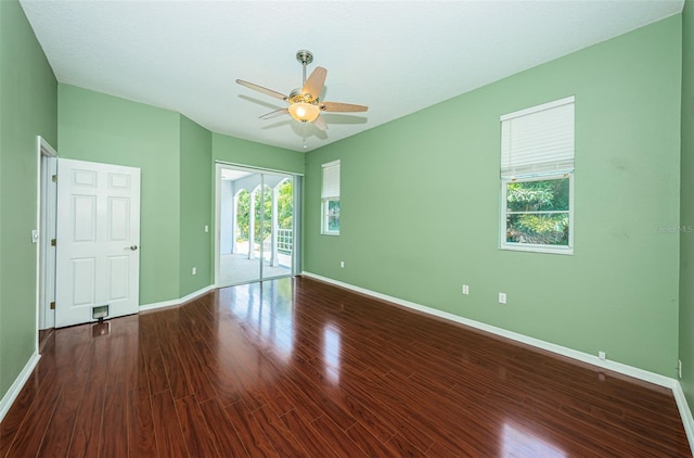 empty room with wood finished floors, a ceiling fan, and baseboards