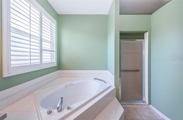 bathroom with a shower stall, a bath, and tile patterned floors