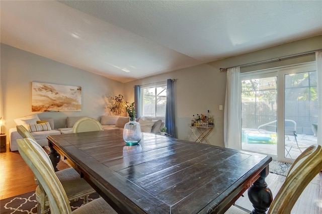 dining area with hardwood / wood-style floors, a healthy amount of sunlight, and vaulted ceiling