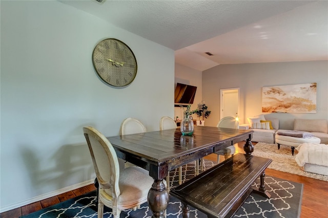 dining area with wood-type flooring and vaulted ceiling