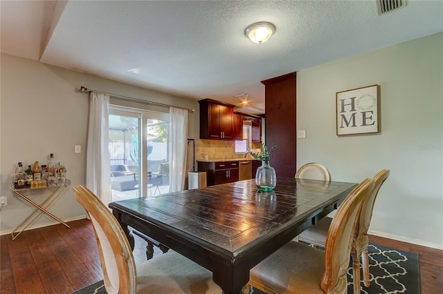 dining area featuring dark wood-type flooring and a textured ceiling