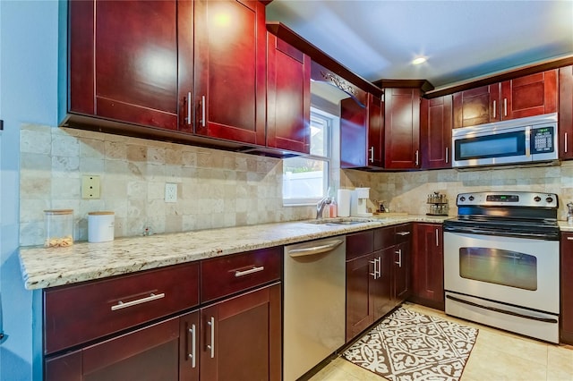 kitchen with decorative backsplash, sink, light stone countertops, and appliances with stainless steel finishes