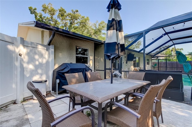 view of patio featuring glass enclosure and a grill