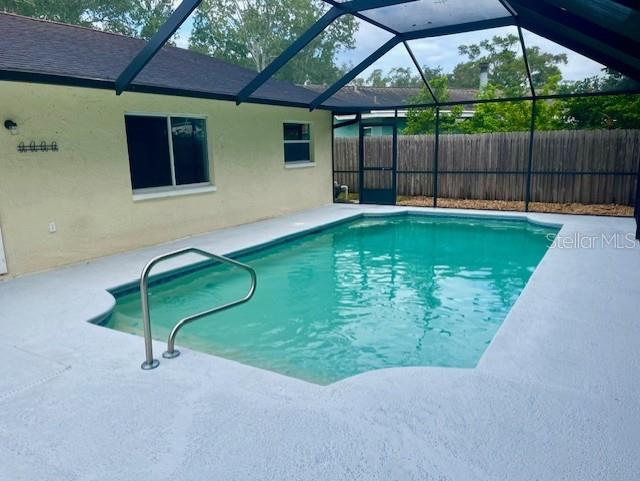 view of swimming pool featuring a lanai and a patio