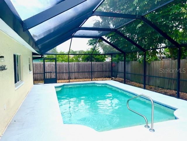 view of swimming pool featuring glass enclosure