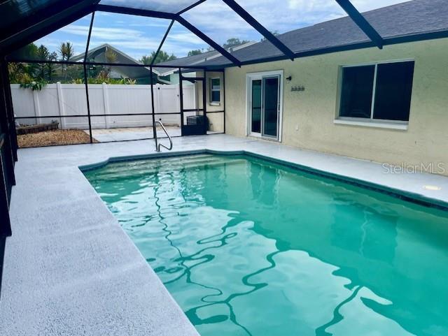 view of swimming pool featuring glass enclosure and a patio area