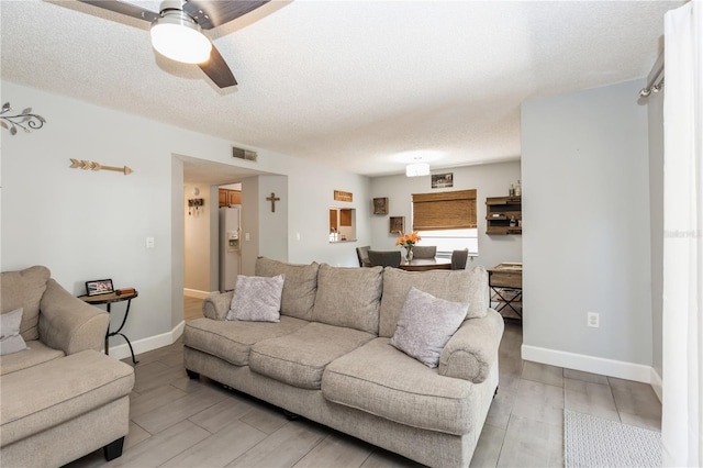 living room with a textured ceiling and ceiling fan