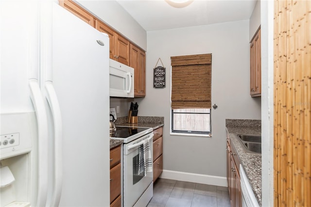 kitchen featuring white appliances, sink, and dark stone counters