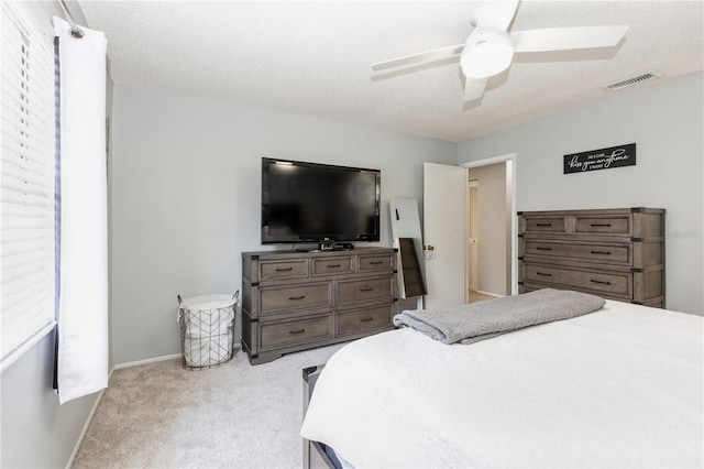 bedroom featuring a textured ceiling, light colored carpet, and ceiling fan